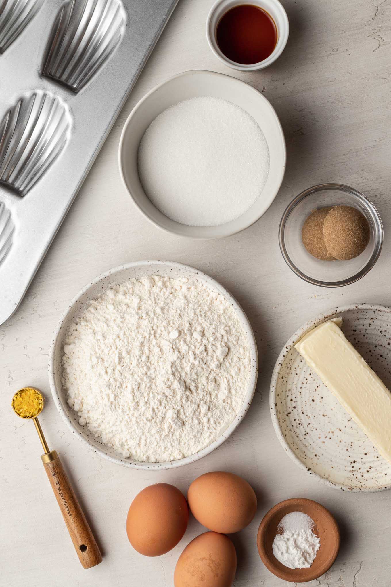 An overhead view of the ingredients needed to make French madeleine cookies. 