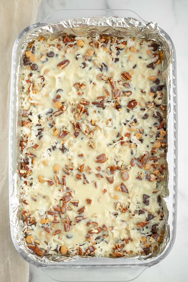 A pan filled with all of the ingredients for magic cookie bars.