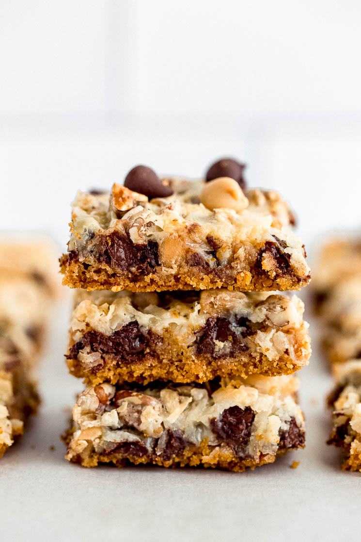 A stack of 7 layer magic cookie bars on a piece of parchment paper.