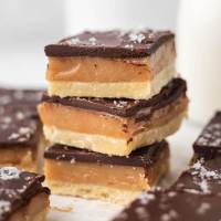 A stack of three millionaire shortbread bars topped with sea salt.