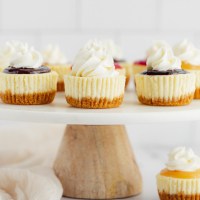 Several mini cheesecakes with different toppings on a marble cake stand.