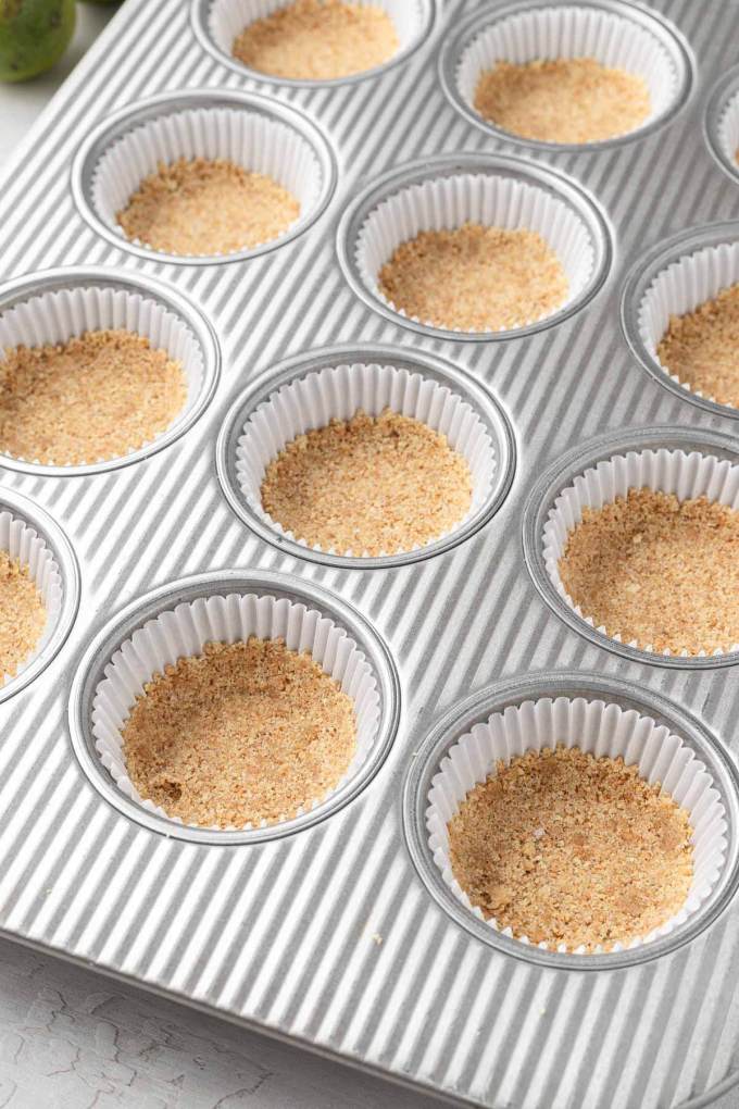 Muffin liners with graham cracker crust pressed into the bottom.