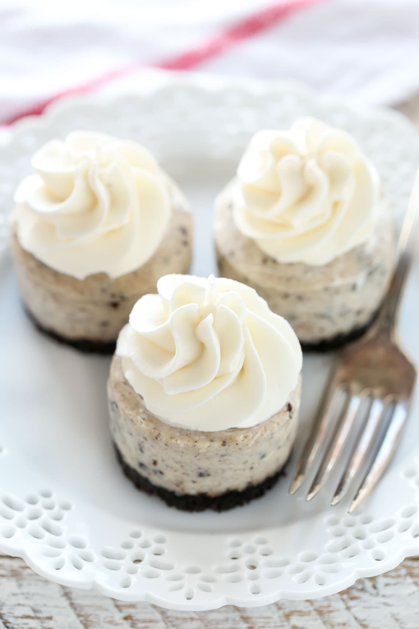 Three oreo cheesecake bites on a white plate with a fork. 