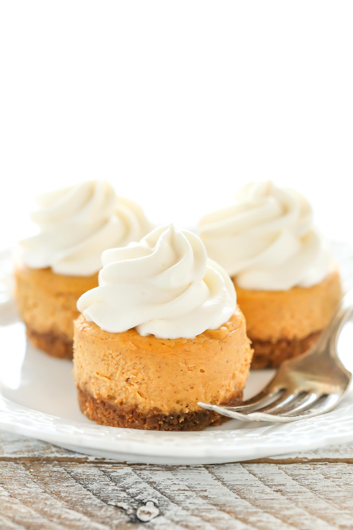 These Mini Pumpkin Cheesecakes feature an easy three ingredient gingersnap cookie crust with a smooth and creamy pumpkin cheesecake filling on top. These are the perfect mini dessert for fall!