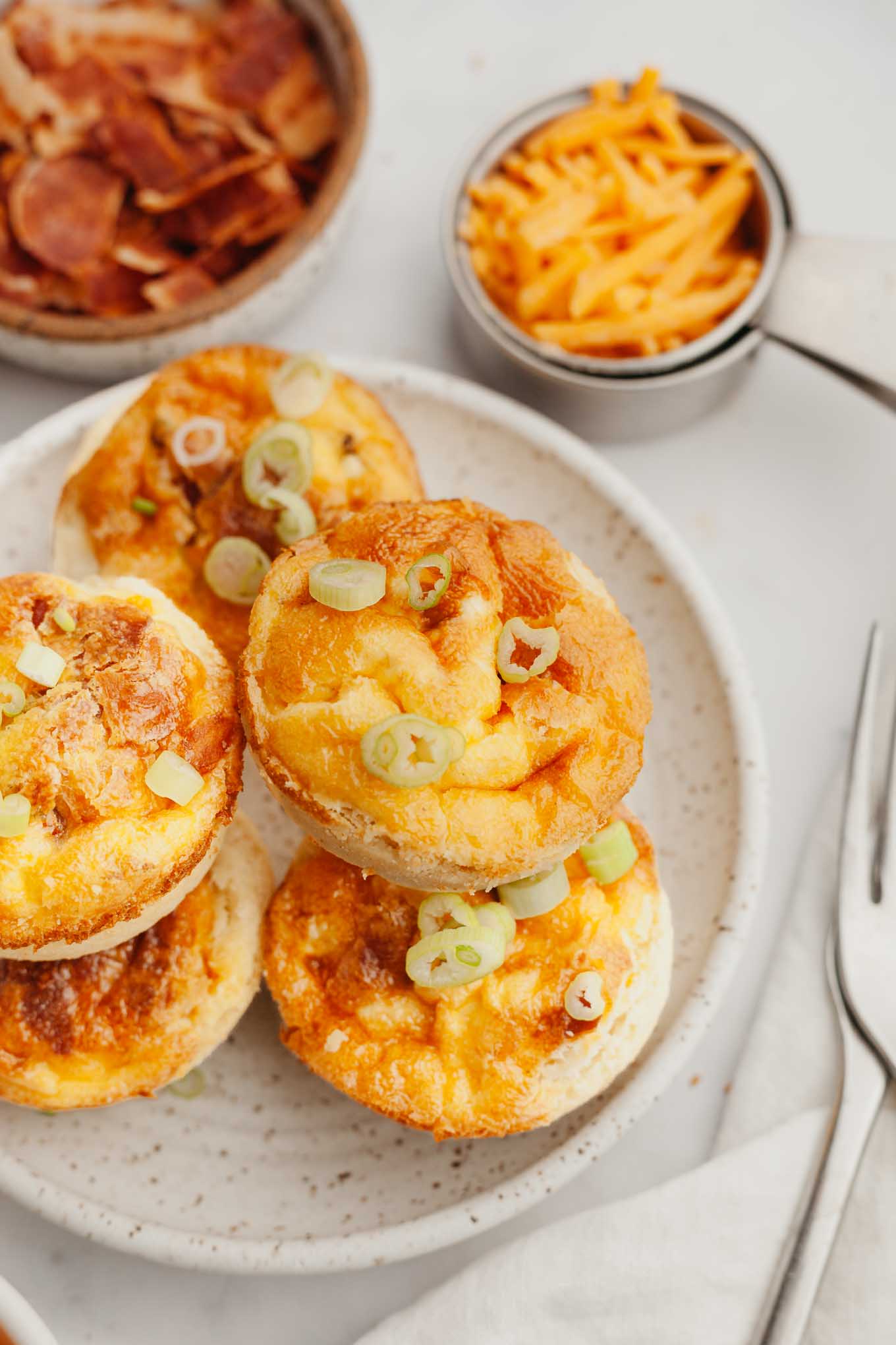 A stack of mini quiches on a speckled white plate. 