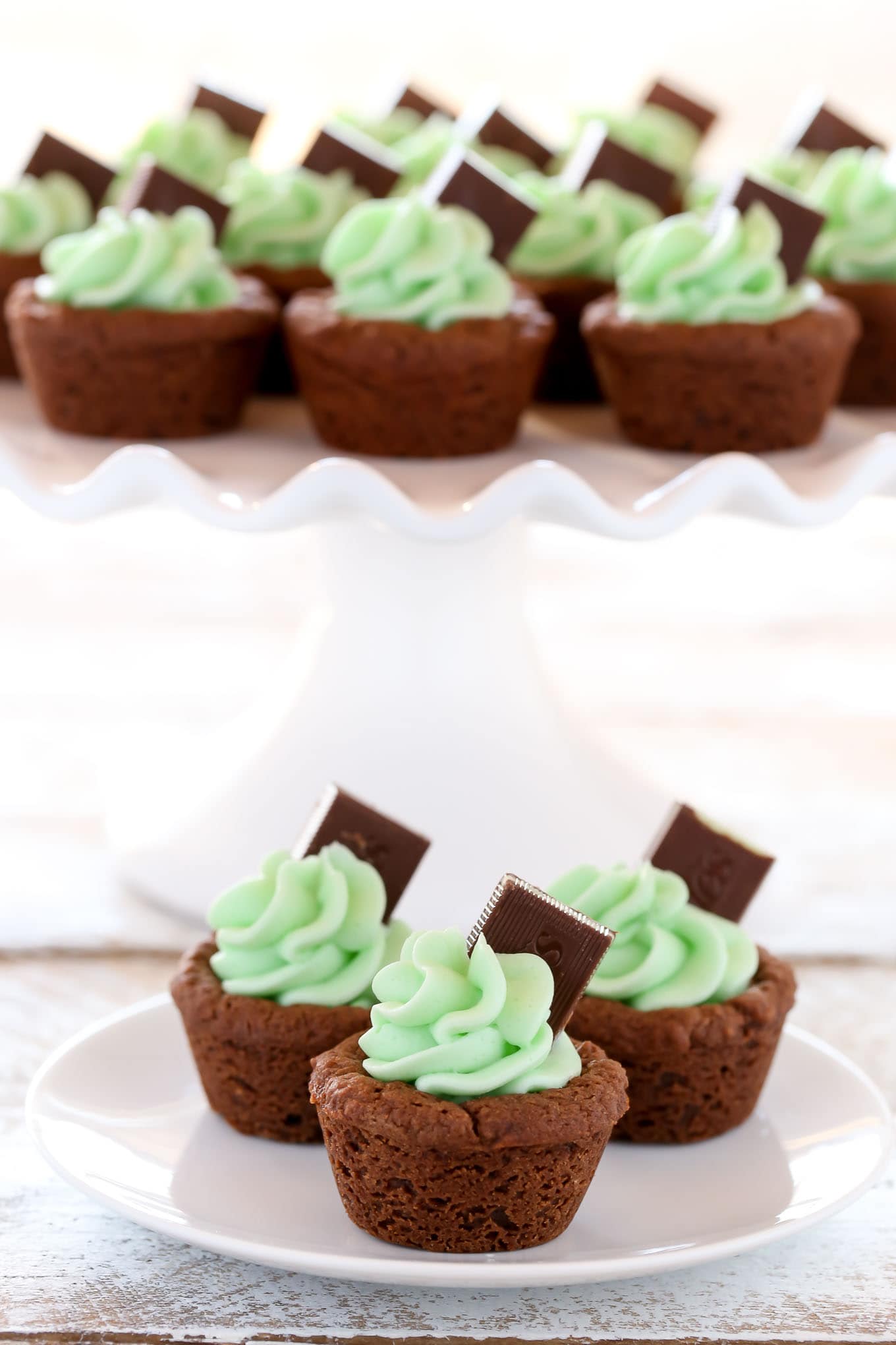 Chocolate cookie cups filled with an easy mint frosting and topped with an andes mint. These Mint Chocolate Cookie Cups are a perfect treat for St. Patrick's Day or mint chocolate lovers!