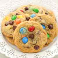 Several M&M's cookies on a decorative white plate.