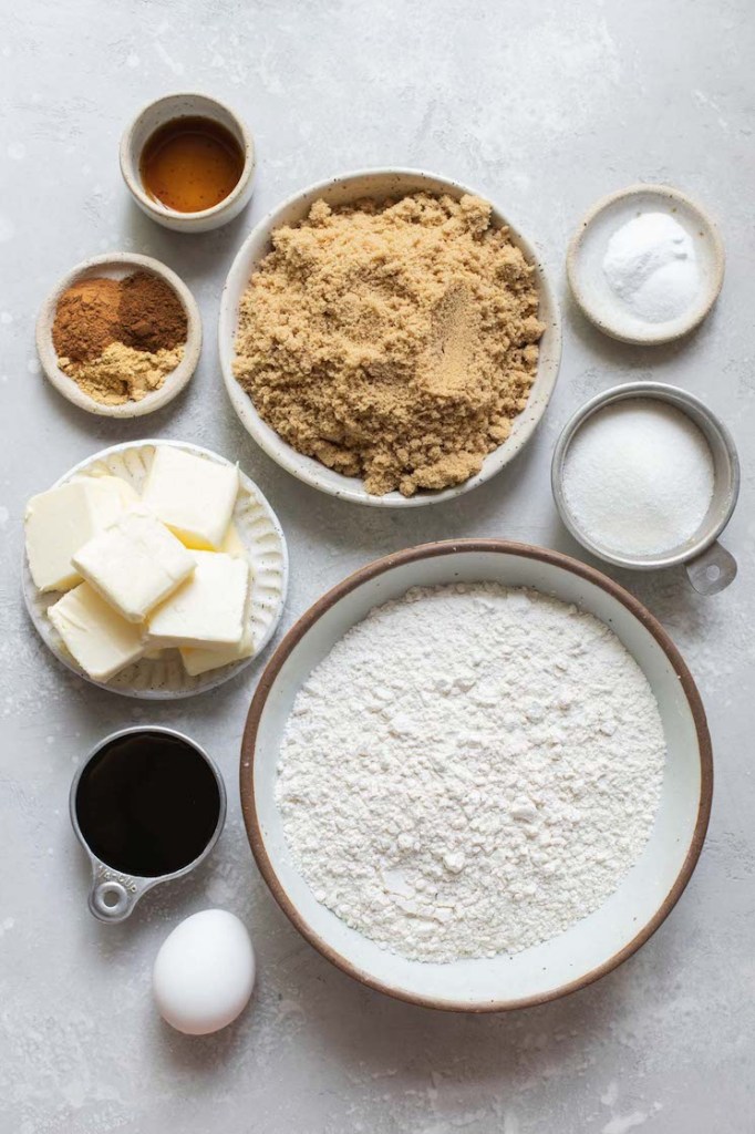 The ingredients needed to make cookies laid out in bowls on top of a rustic gray surface.