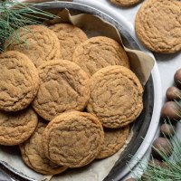 A baking pan lined with parchment paper and filled with soft molasses cookies.