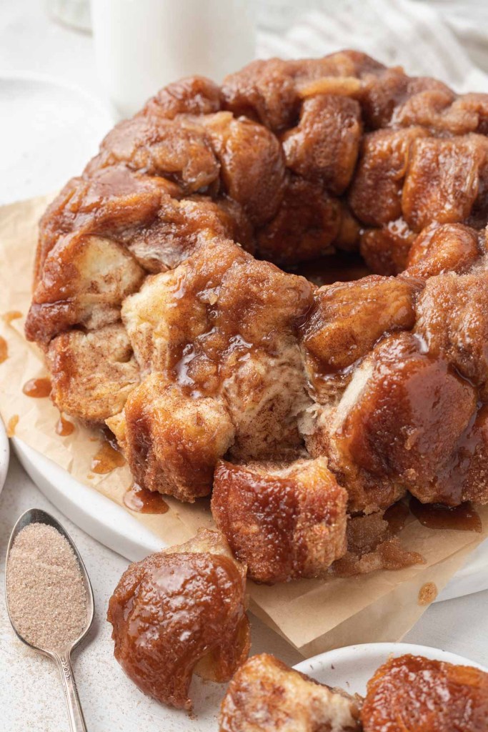 Monkey bread with pieces pulled off of it, on parchment paper. 