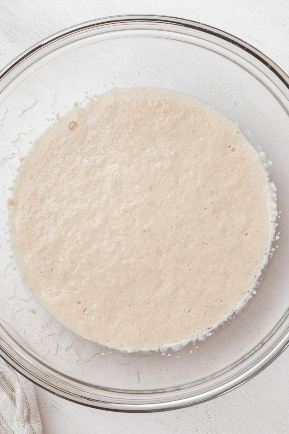 Overhead view of yeast proofing in a glass mixing bowl.