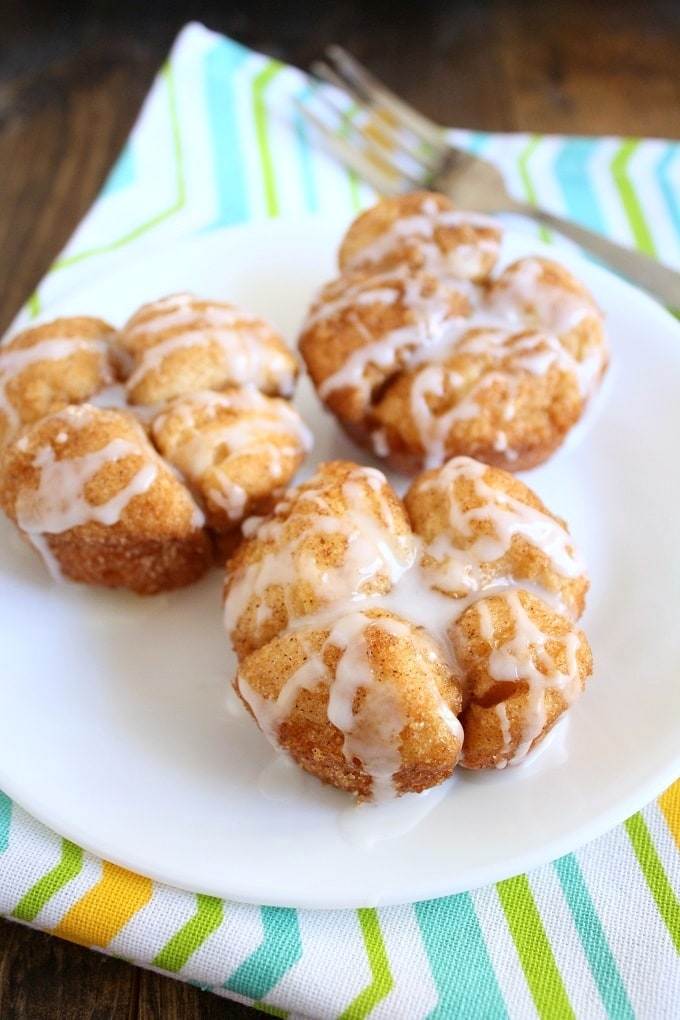 Three Monkey Bread Muffins on a white plate. A fork and striped napkin rest near the plate. 