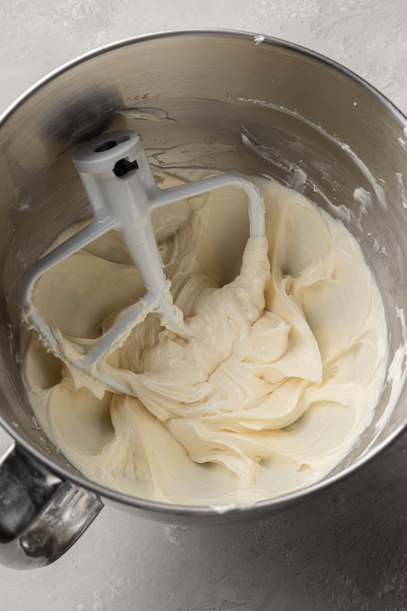 An overhead view of no bake cheesecake filling in a mixing bowl, with a paddle attachment. 