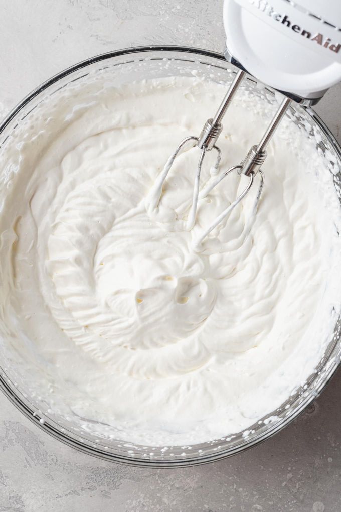 An overhead view of whipped cream in a mixing bowl.