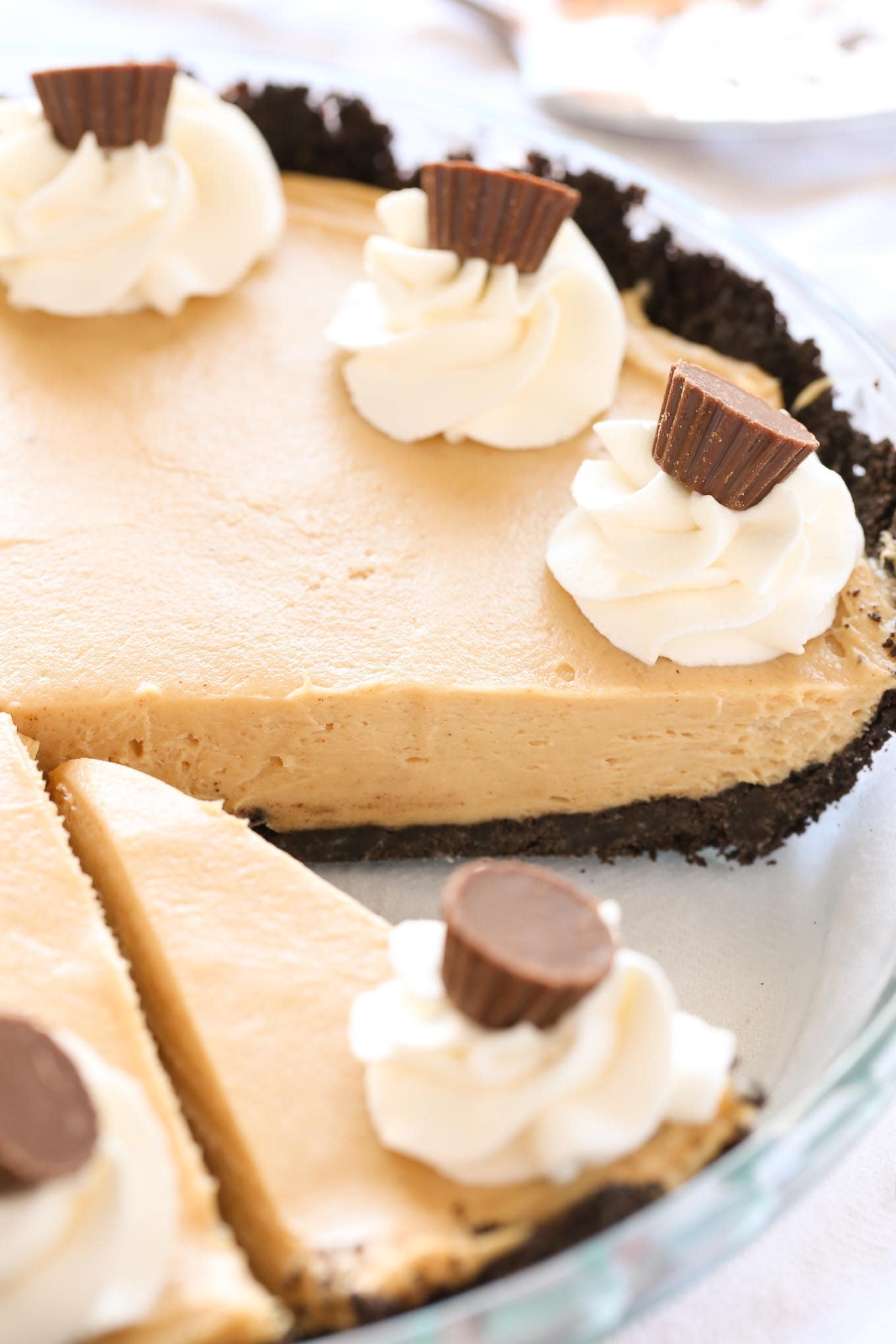 A no bake peanut butter pie in a glass pie plate. One slice is missing. 