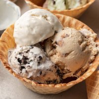 Three scoops of no churn ice cream in a waffle cone bowl.