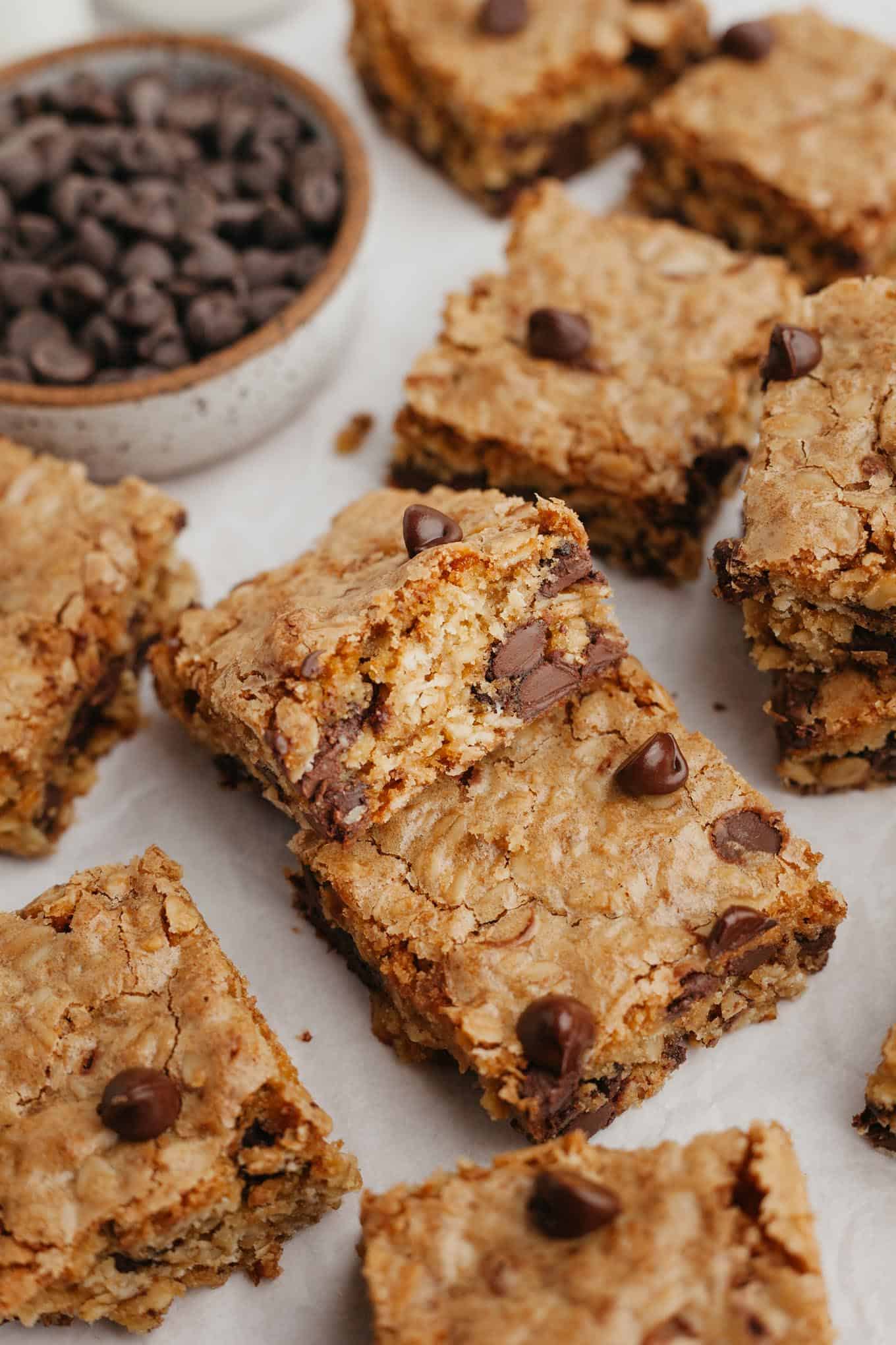 Oatmeal bar cookies arranged haphazardly on a white surface. 