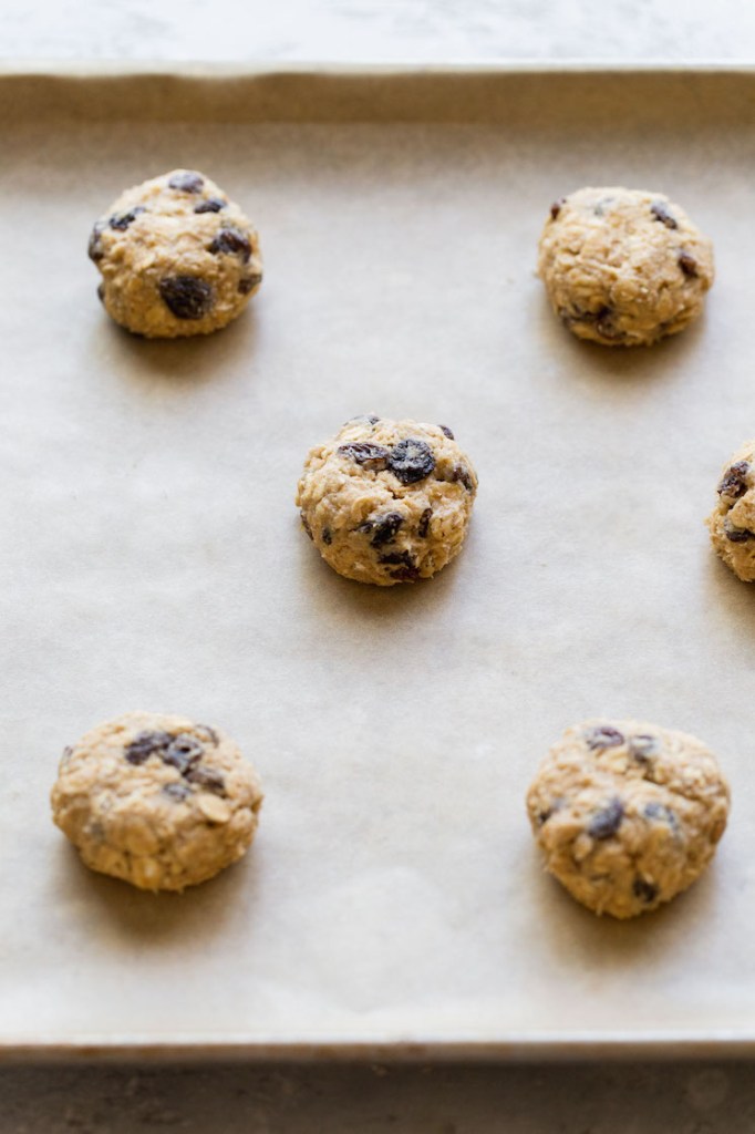 A baking sheet lined with parchment paper holding cookie dough balls that have been pressed down slightly.