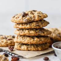 A stack of oatmeal raisin cookies on top of a small cooling rack lined with parchment paper.