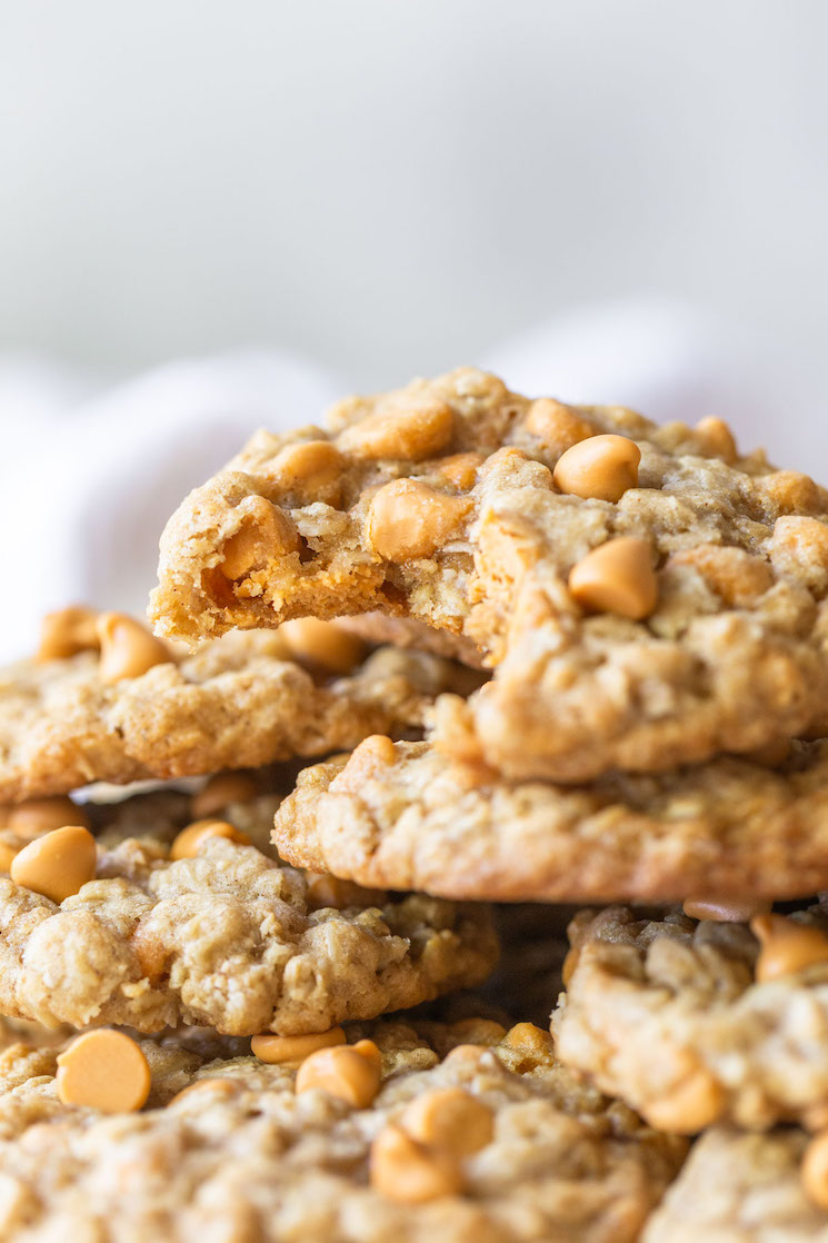 A stack of oatmeal scotchies with one having a bite taken out to see the inside detail of the cookie.