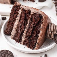 A slice of Oreo cake on a white speckled plate.