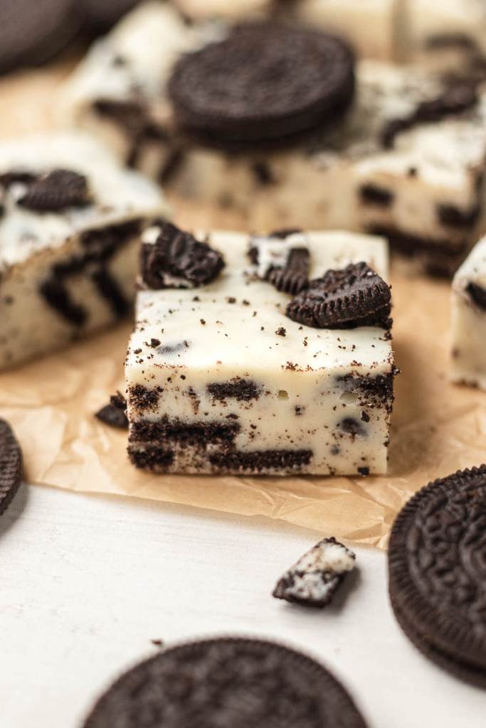 Slices of no bake fudge with Oreos on parchment paper. 