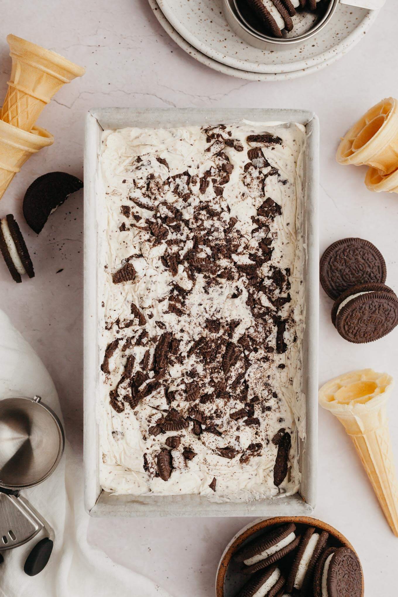 An overhead view of Oreo cookie ice cream in a metal loaf pan, surrounded by Oreos. 