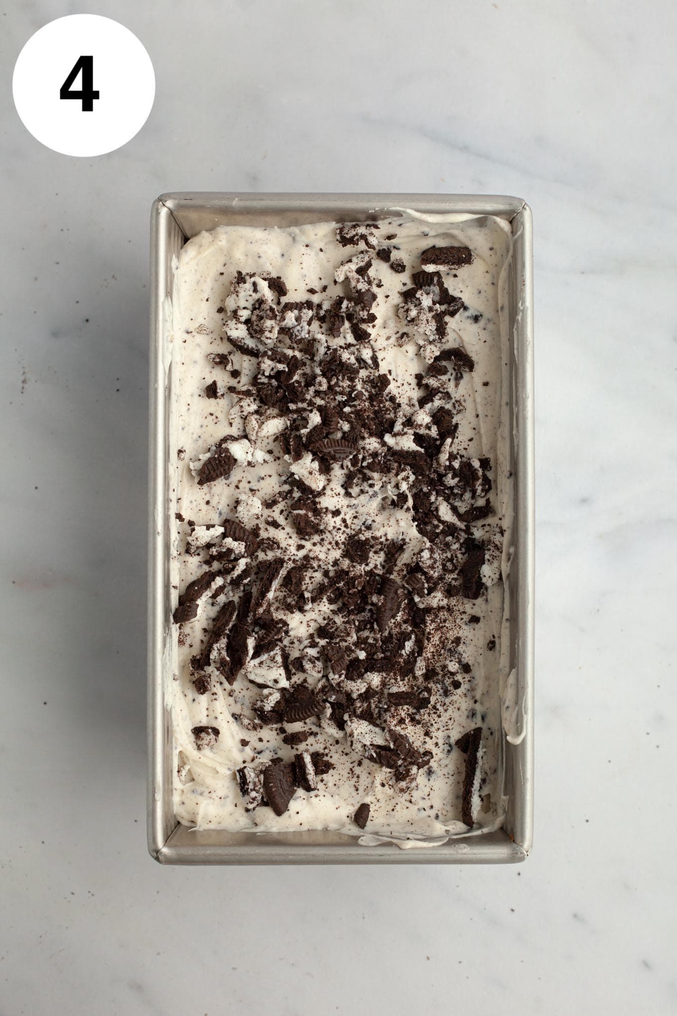 An overhead view of Oreo ice cream in a metal loaf pan. 