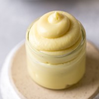 A small glass jar filled with vanilla pastry cream. The jar rests on an overturned bowl.