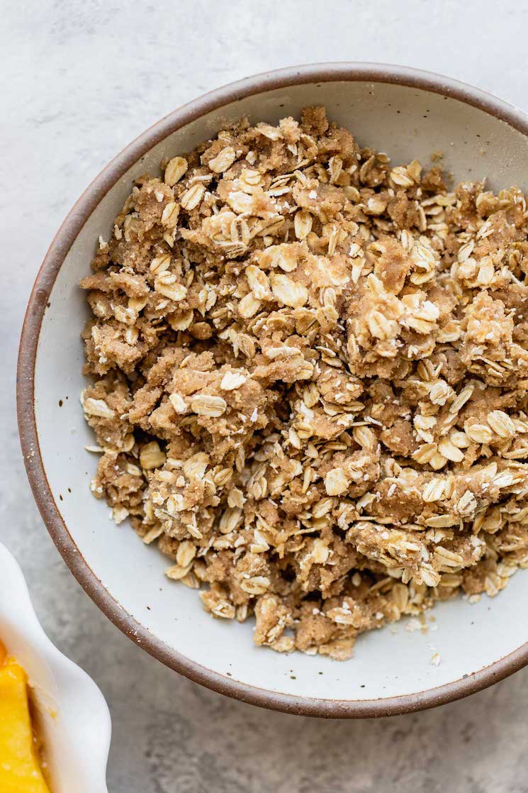 A white bowl filled with brown sugar oat topping.