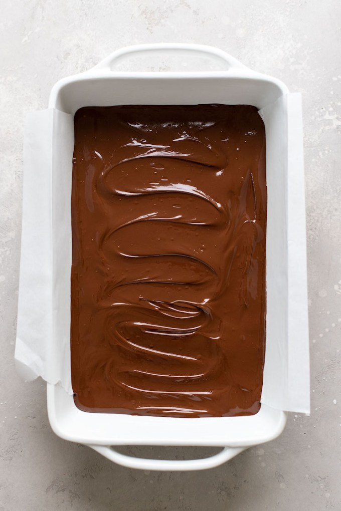 Overhead view of no bake chocolate peanut butter bars in a large baking dish. The bars have not yet set.