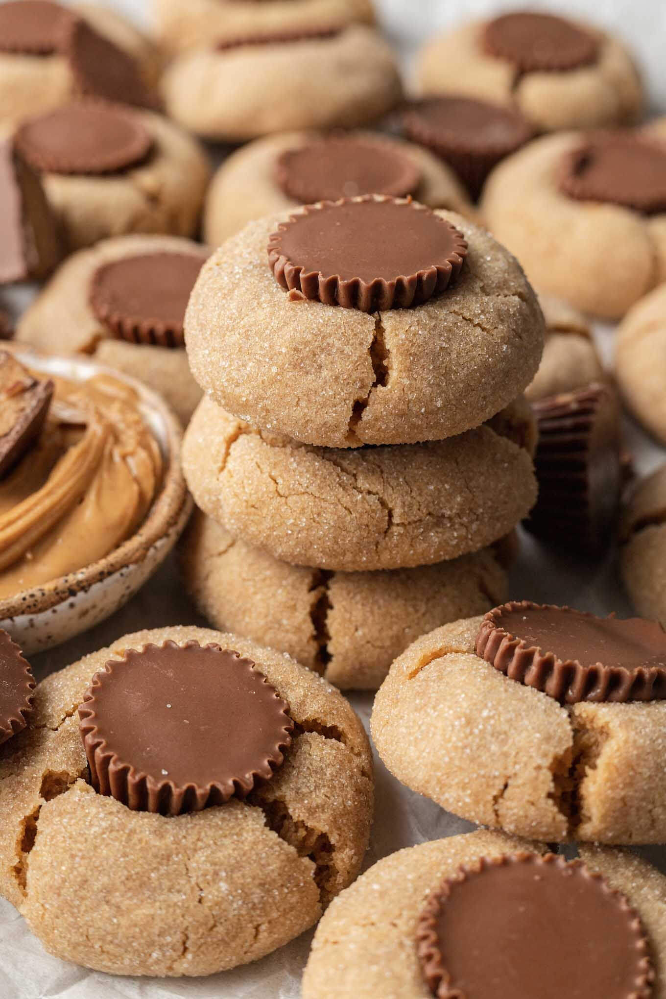 A stack of three mini peanut butter cup cookies, surrounded by additional cookies. 