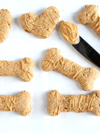 Overhead view of homemade peanut butter dog treats in various shapes. A knife with peanut butter on it rests in the middle.