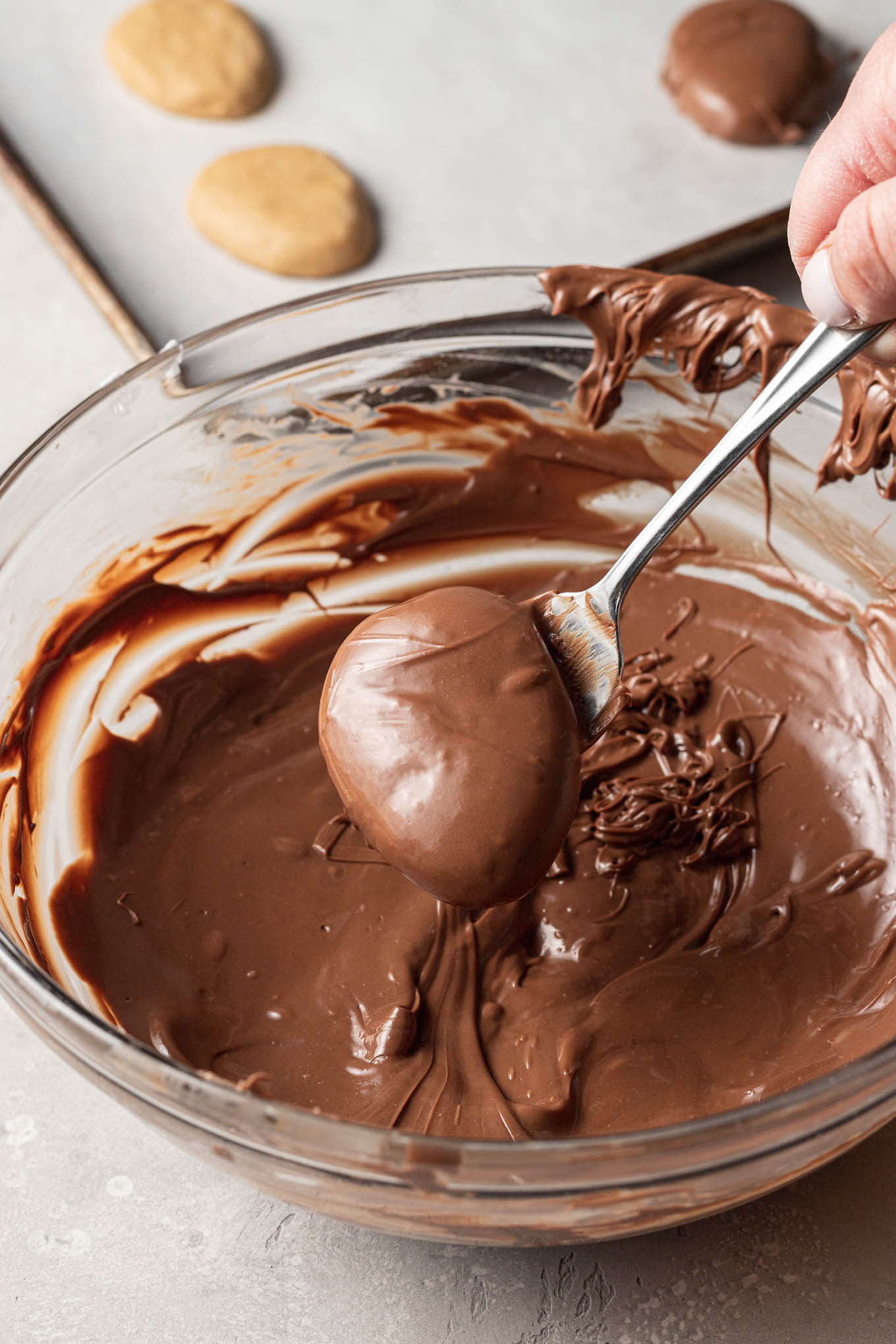 A homemade peanut butter egg being dunked in melted chocolate.