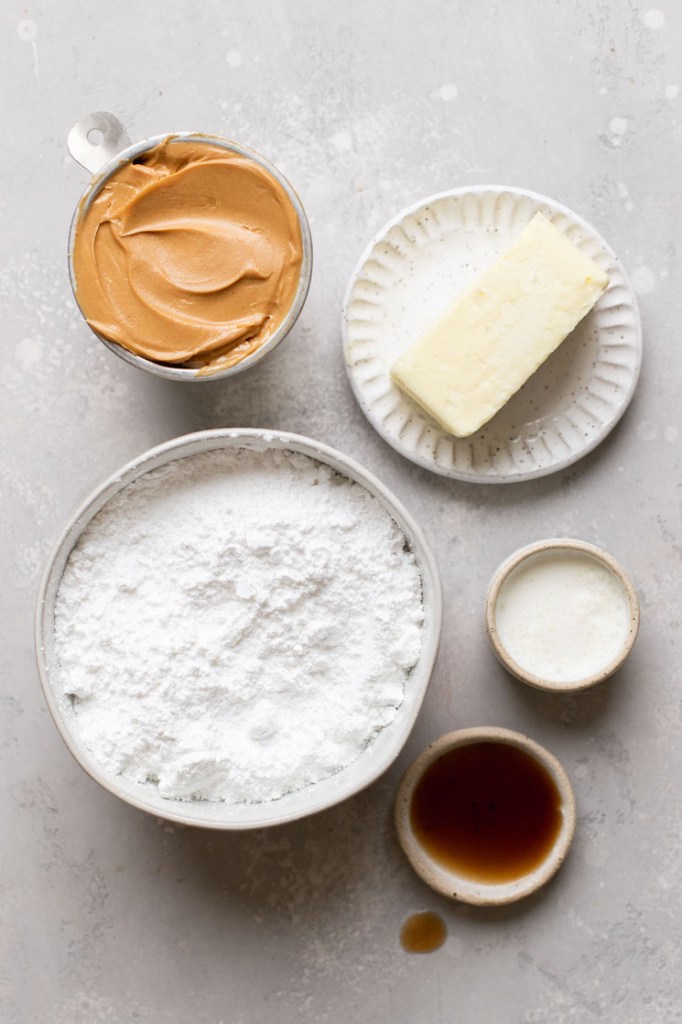 The ingredients needed to make peanut butter frosting laid out on a gray surface.