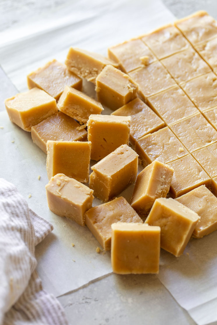 Peanut butter fudge cut into pieces on parchment paper.