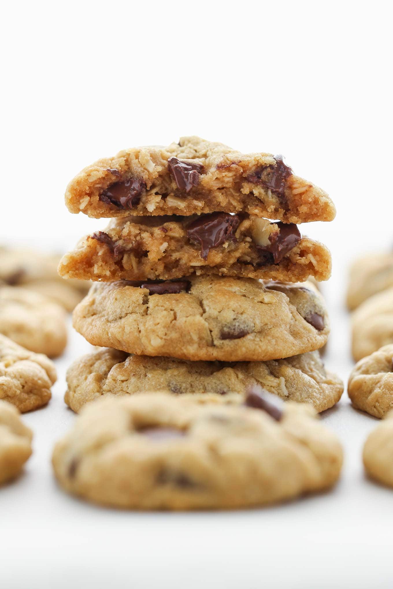 A stack of peanut butter oatmeal chocolate chip cookies with more cookies surrounding them.