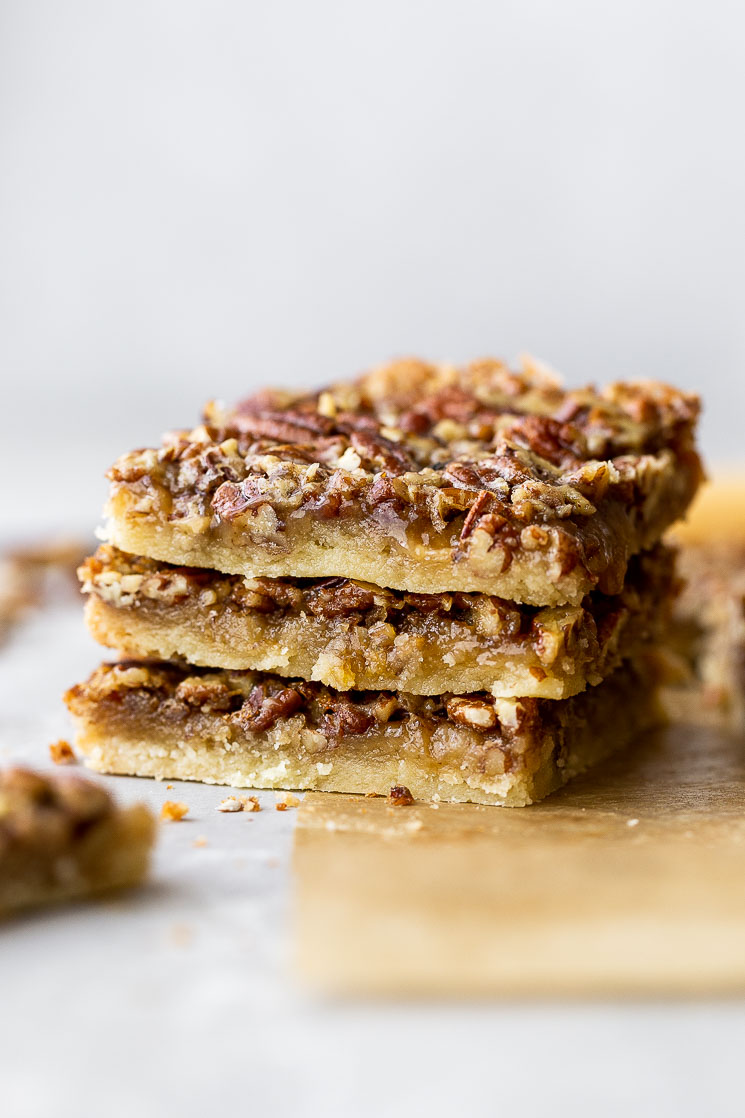 A stack of three pecan pie bars on brown parchment paper.