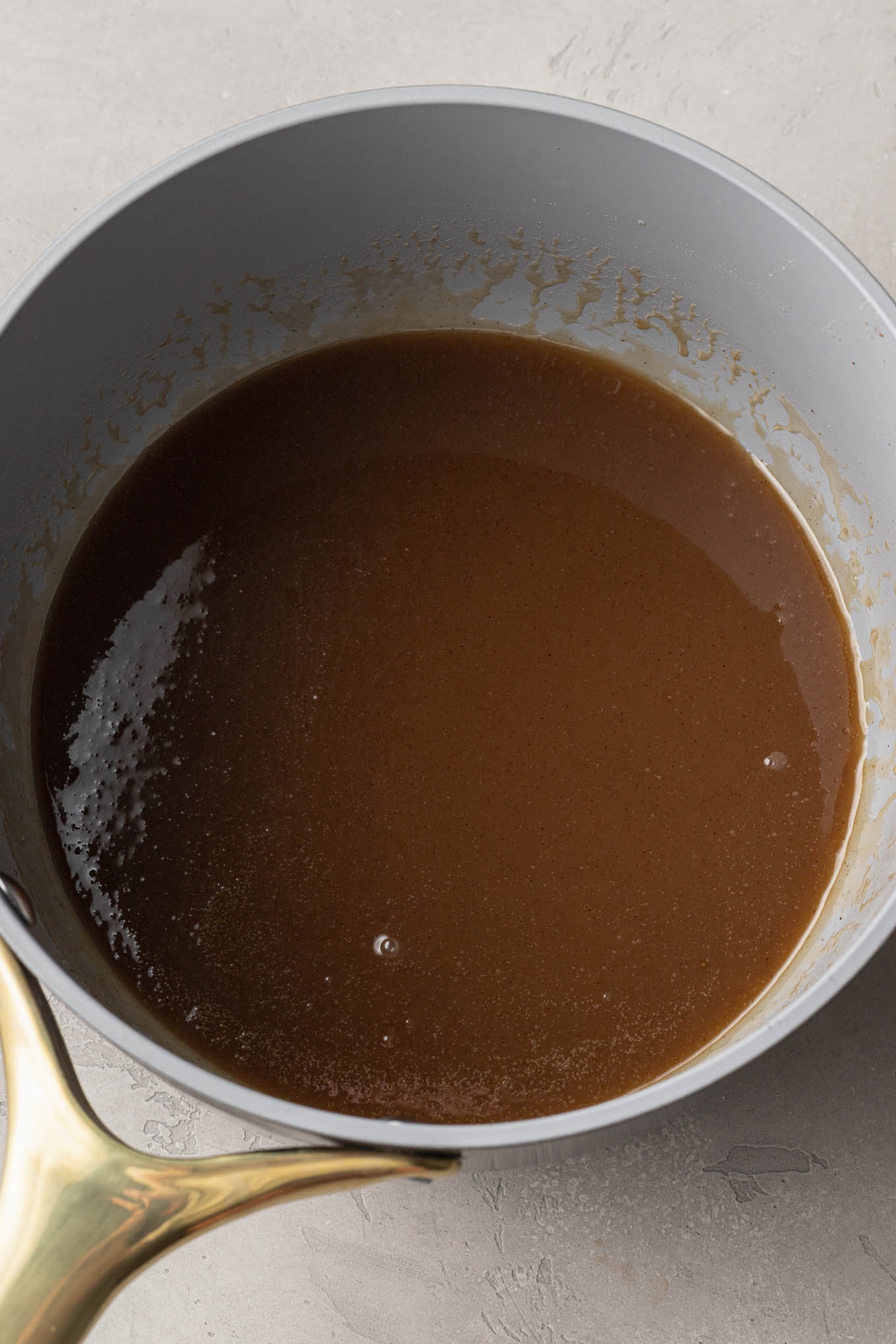 An overhead view of melted cinnamon, butter, and sugar in a saucepan. 