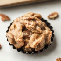 Several pecan pralines in a small tin.