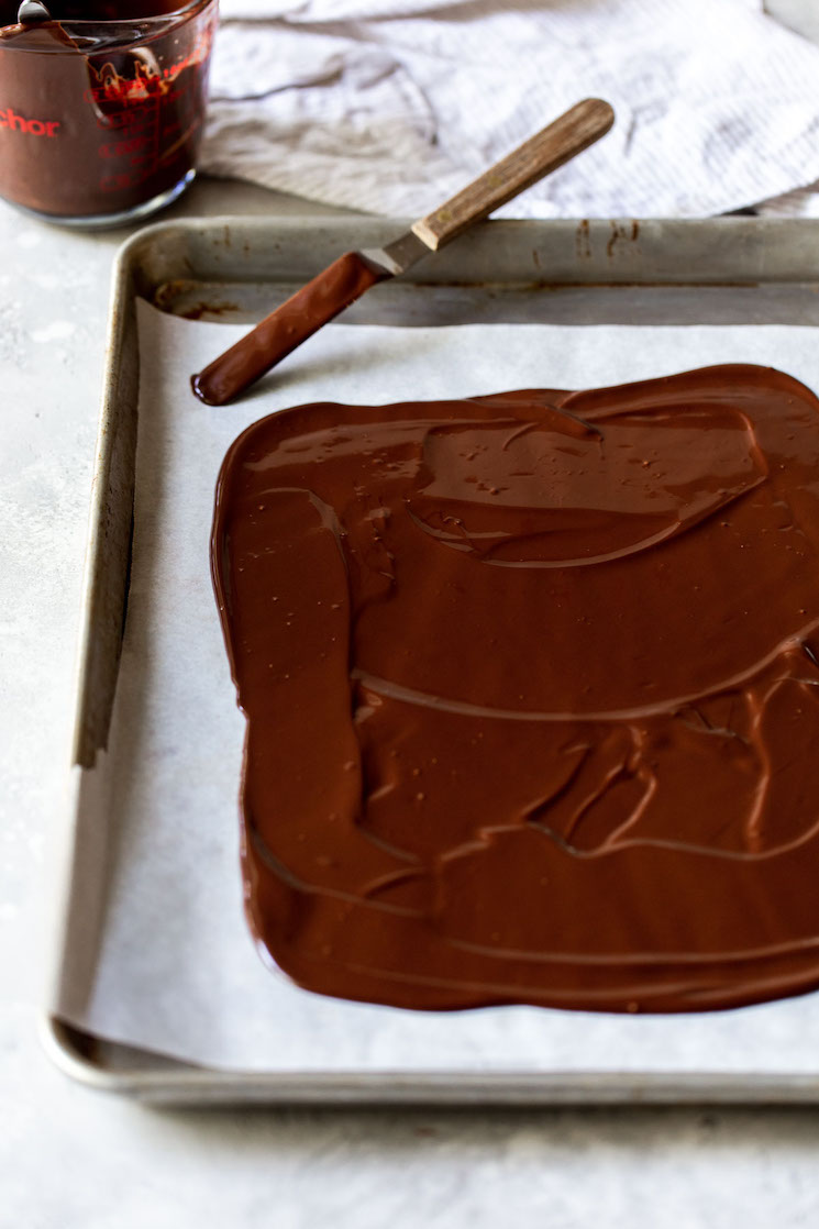 A layer of semi-sweet chocolate spread onto a piece of parchment paper.