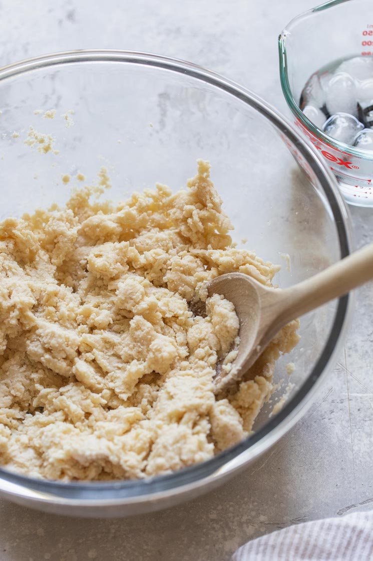 A glass bowl with the pie crust ingredients all mixed together.