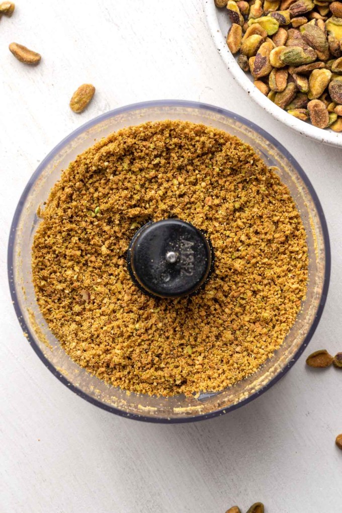 An overhead view of crushed pistachios in a food processor.