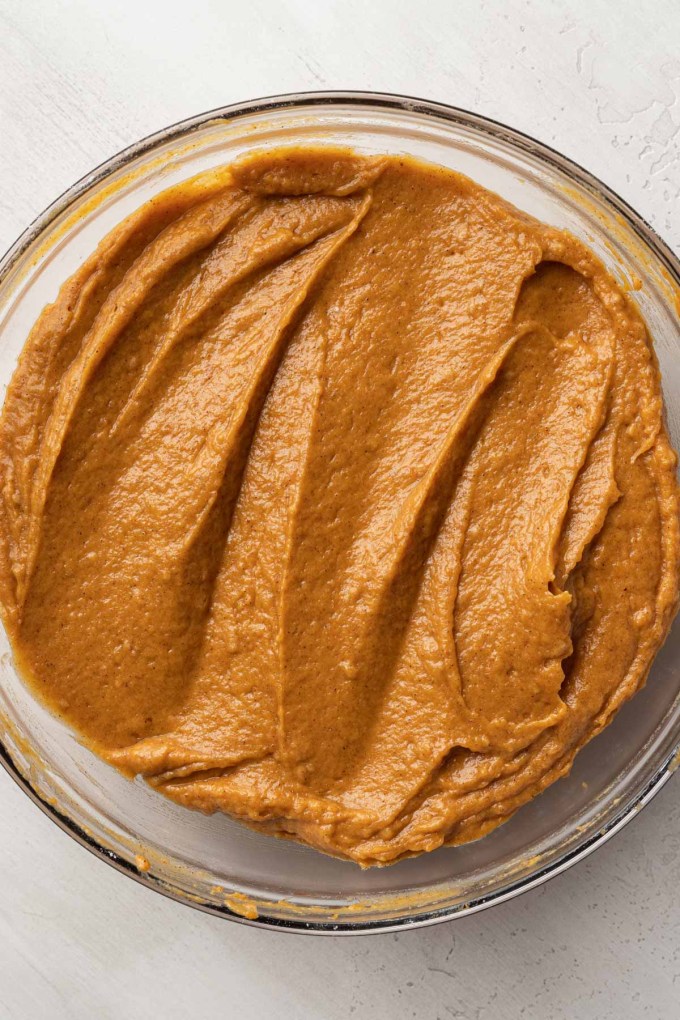 An overhead view of pumpkin batter in a glass mixing bowl. 