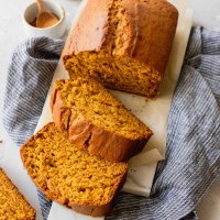 A loaf of pumpkin bread that has been sliced on a marble serving tray.