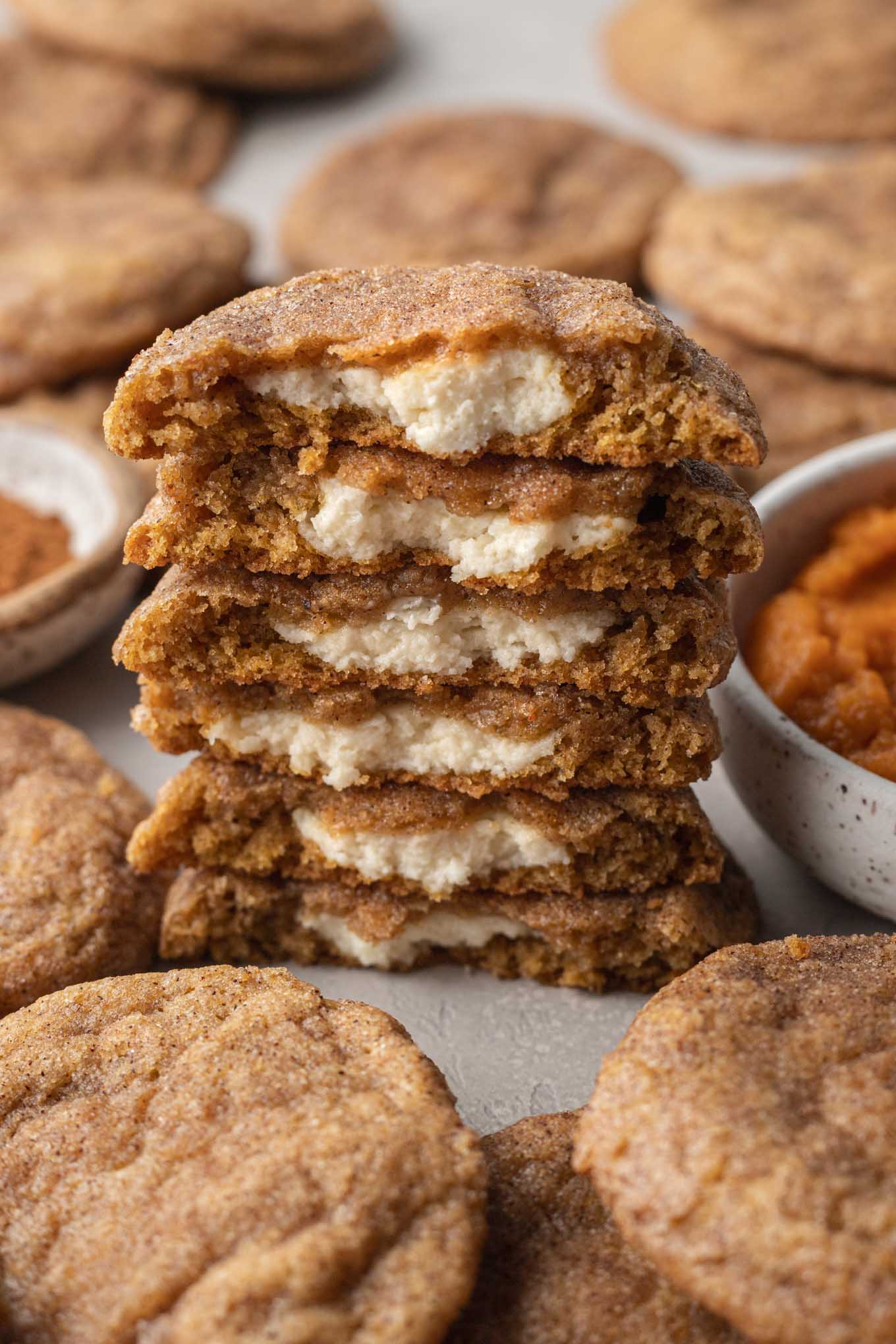 A stack of halved pumpkin cheesecake cookies, with the filling showing. 