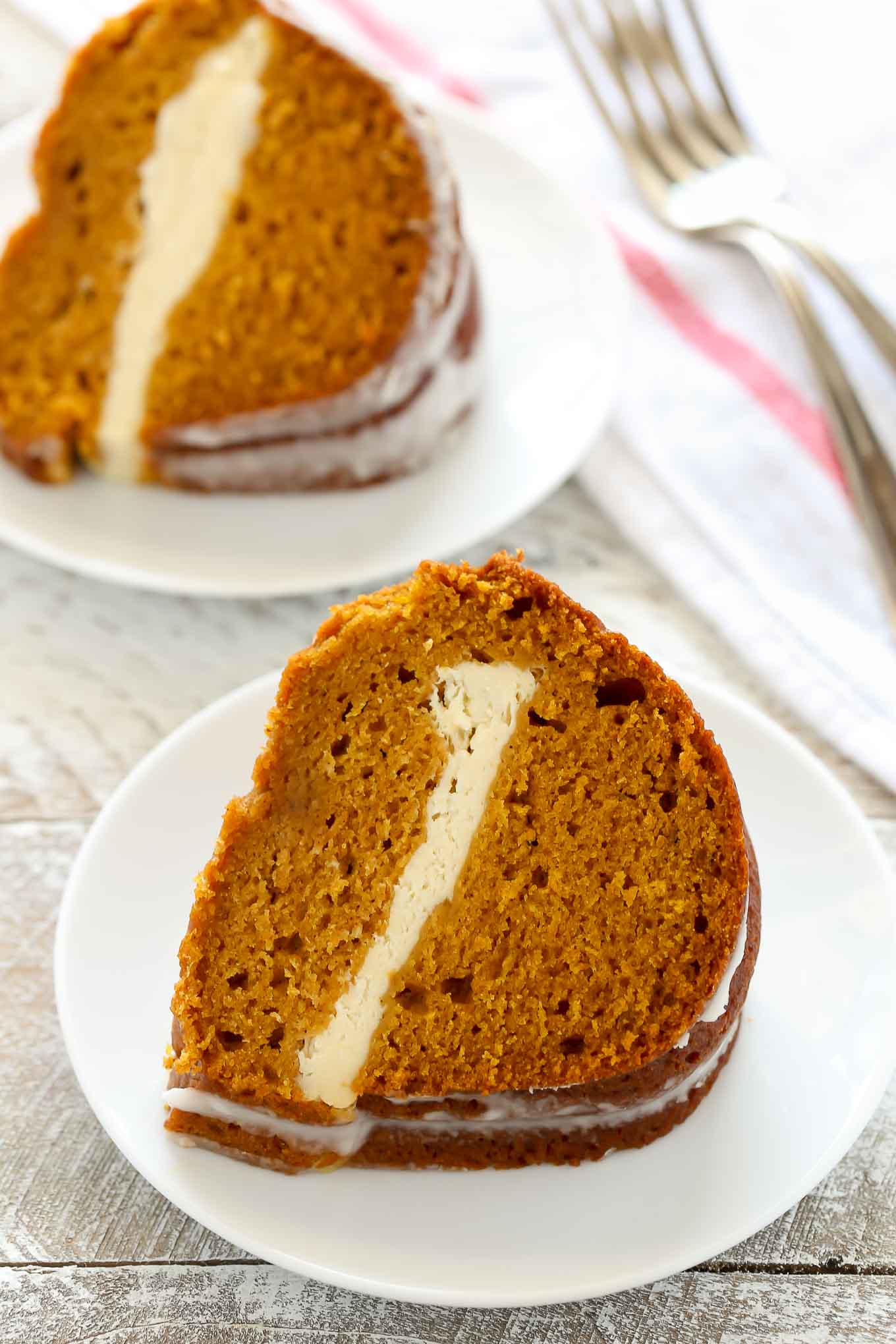 Two slices of pumpkin bundt cake on white plates. 