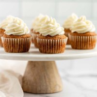 Pumpkin cupcakes sitting on top of a marble cake stand.