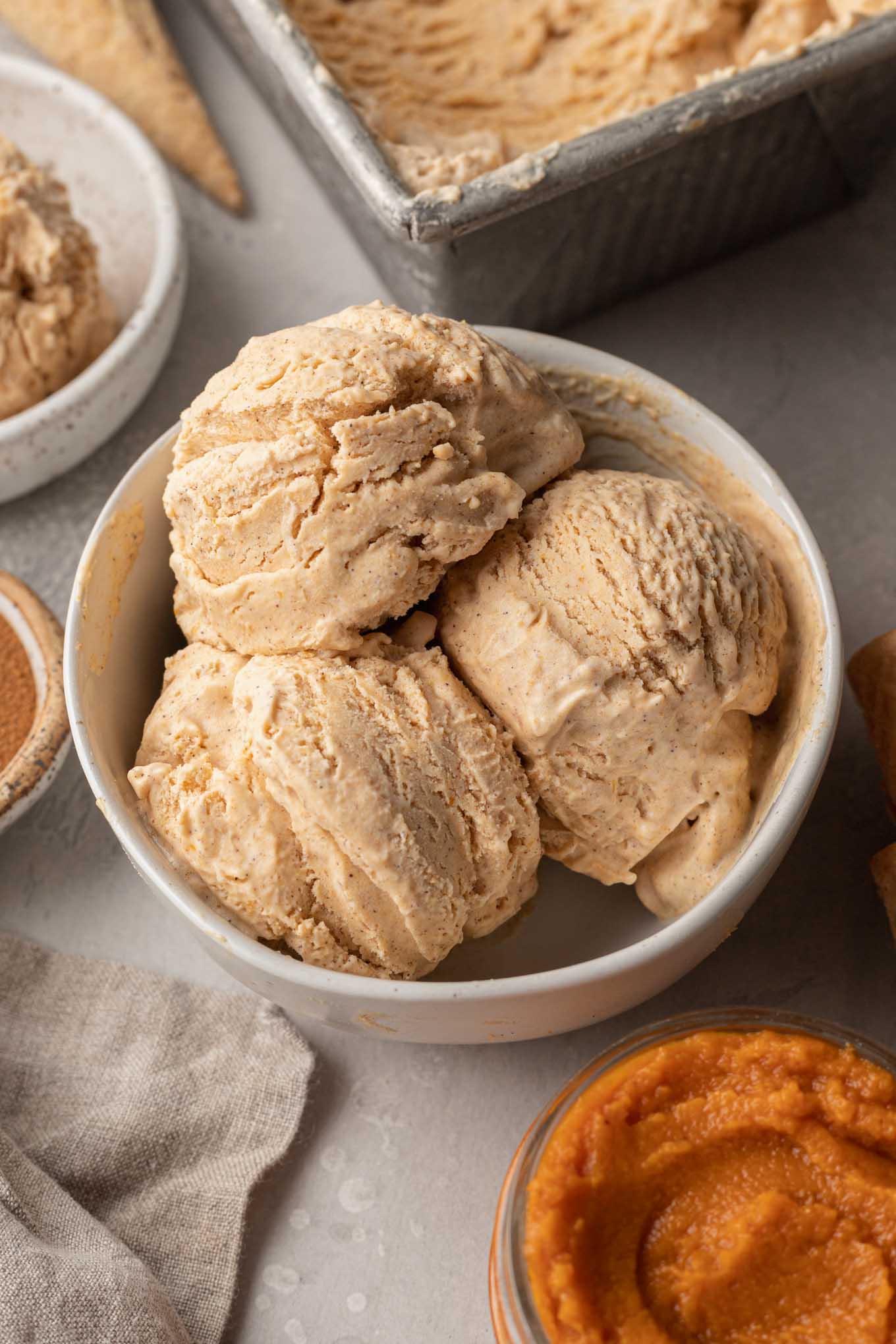 Three scoops of homemade pumpkin ice cream in a white bowl. 