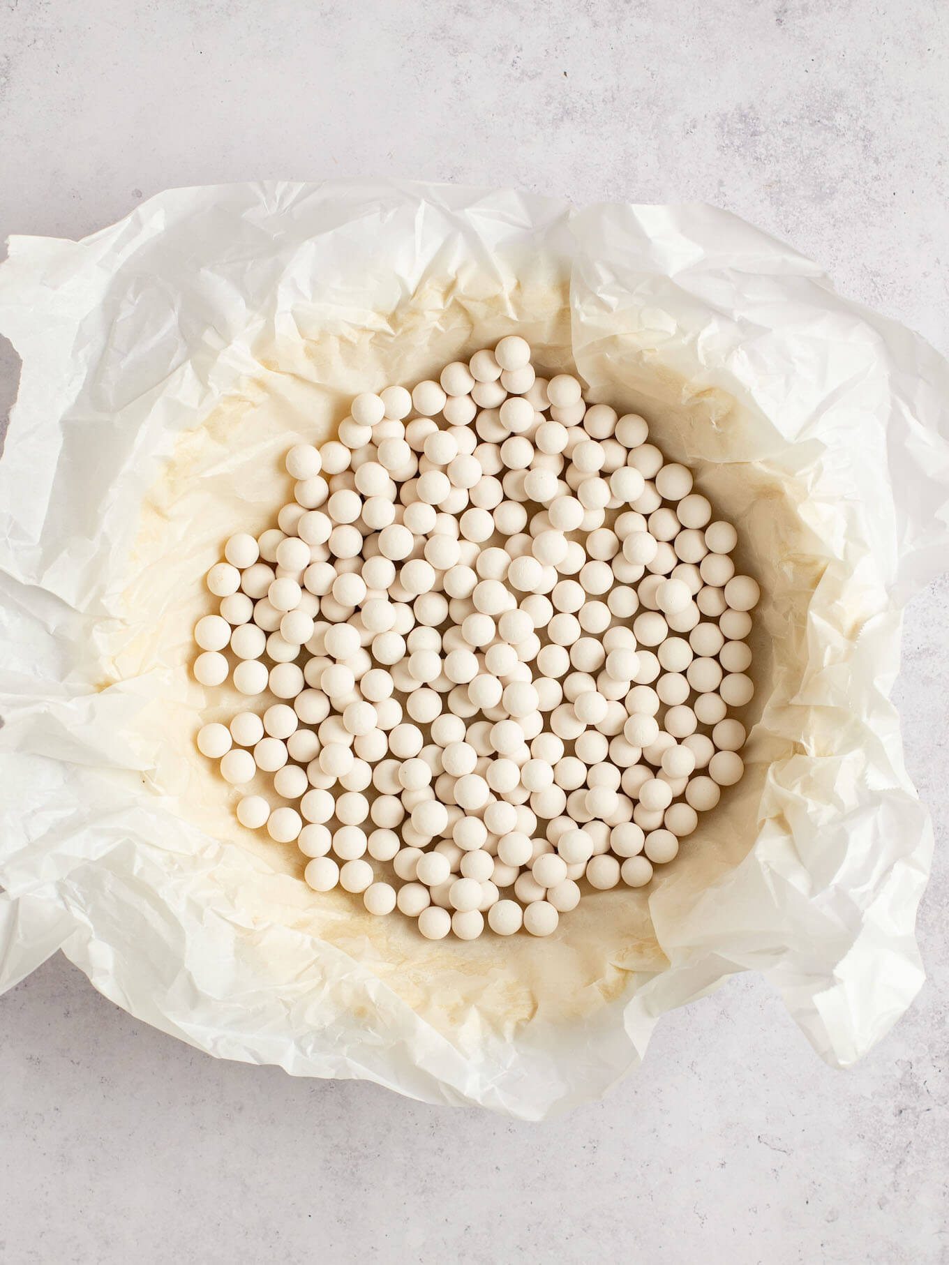 A pie crust lined with parchment paper and filled with pie weights.